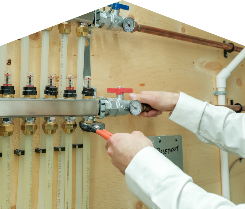 Romaniuk HVAC specialist performing boiler repair, adjusting internal components of a residential unit with visible copper piping and control wiring. Romaniuk HVAC specialist performing boiler repair, adjusting internal components of a residential unit with visible copper piping and control wiring.