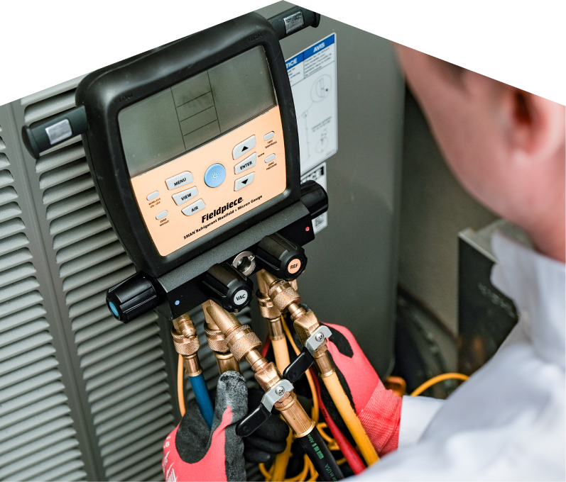 A Romaniuk home service crew member uses a digital manifold gauge to check refrigerant levels on an HVAC unit for service. A Romaniuk home service crew member uses a digital manifold gauge to check refrigerant levels on an HVAC unit for service.