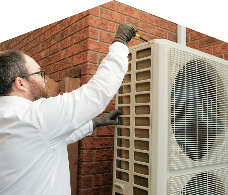 Romaniuk HVAC specialist using a screwdriver to complete a heat pump installation beside a brick wall. Romaniuk HVAC specialist using a screwdriver to complete a heat pump installation beside a brick wall.