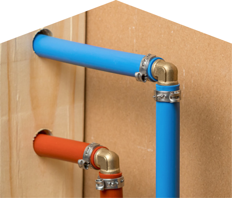 Romaniuk kitec plumbing system with blue and orange plastic pipes connected by brass fittings and metal clamps, mounted on a wooden panel. Romaniuk kitec plumbing system with blue and orange plastic pipes connected by brass fittings and metal clamps, mounted on a wooden panel.