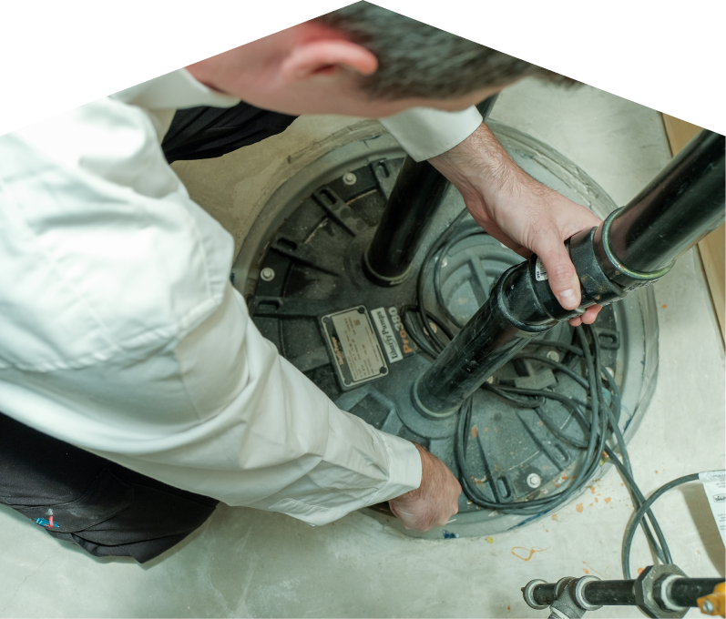 Romaniuk sump pump specialist secures discharge piping on a sealed basin during a sump pump installation in a basement utility area. Romaniuk sump pump specialist secures discharge piping on a sealed basin during a sump pump installation in a basement utility area.