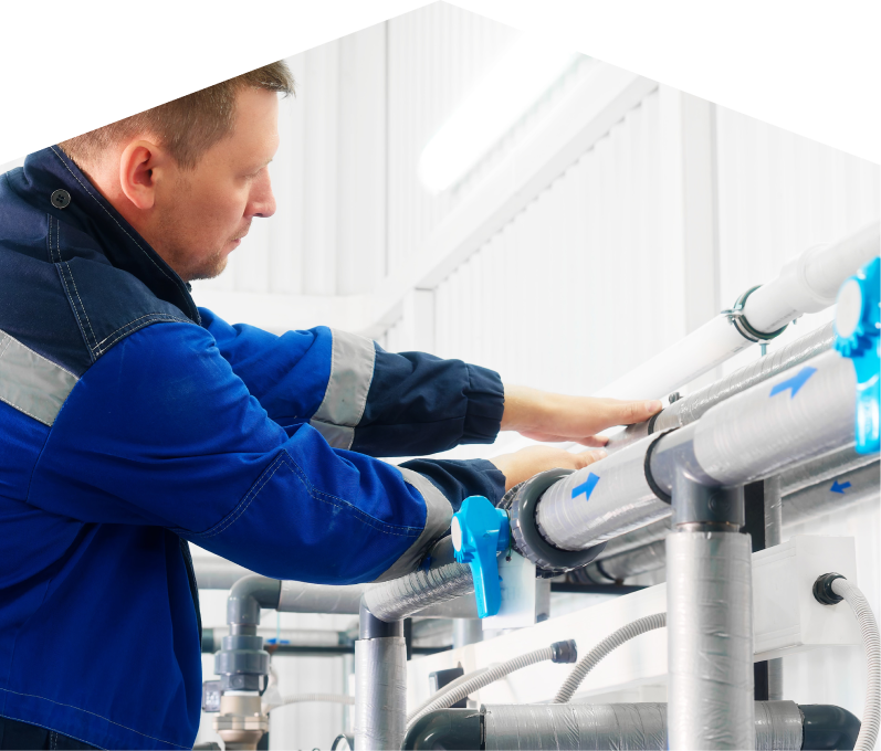 Romaniuk water damage and restoration specialist in a blue uniform adjusts insulated piping on a water system inside a bright utility room. Romaniuk water damage and restoration specialist in a blue uniform adjusts insulated piping on a water system inside a bright utility room.
